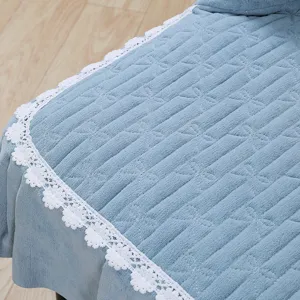 Close-up detail of blue stretch chair cover featuring soft quilted texture and white lace trim.
