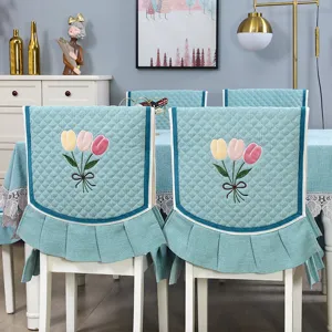 Vista dettagliata di coprisedie da pranzo trapuntate e tovaglia con ricamo di tulipani teal.