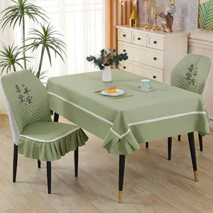 Green fabric tablecloth and matching dining chair covers set with elegant white trim details.