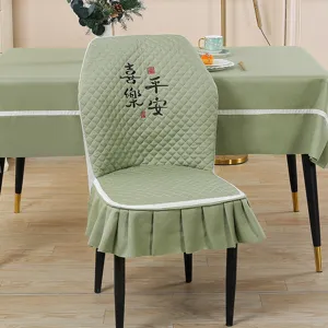 Green quilted elastic chair cover with ruffles and matching tablecloth set for dining room home.