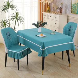 Detailed view of blue tablecloth and chair cover set with white border and embroidery.