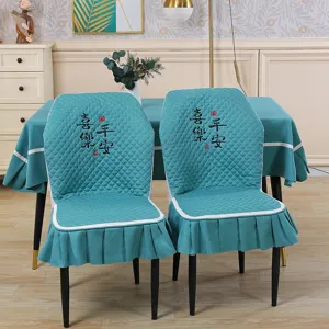 Detail view of the quilted teal chair cover with elegant embroidery and ruffle hem design.