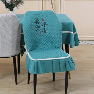Green quilted dining chair cover detail, elegant embroidery design for home decor.