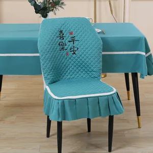 Detail view of the turquoise quilted dining chair cover with elegant Chinese embroidery and skirt design.