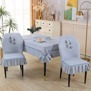 Gray quilted dining chair cover and tablecloth set with traditional embroidered text.