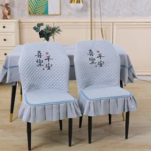 Detail view of stretchy quilted dining chair cover with ruffle skirt and back embroidery.