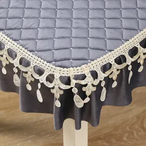 Detail shot of grey quilted velvet tablecloth with elegant gold lace trim for dining table decor.