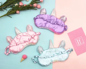 Detailed view of three colorful plush unicorn sleep masks in pink, blue, and purple.