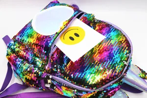 Close-up of vibrant rainbow sequin backpack with unicorn horn and cute heart patch