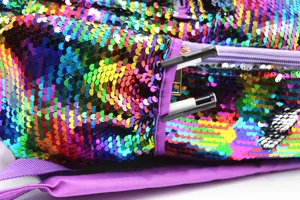 Close-up detail of a colorful rainbow sequin backpack featuring a side zipper pocket