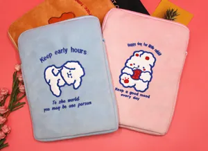 Close-up of cute cartoon plush laptop sleeve with dog and rabbit embroidery details