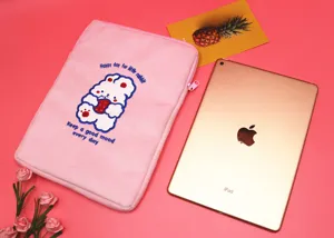 Close-up of pink plush laptop sleeve with cute embroidered rabbit and iPad prop for scale