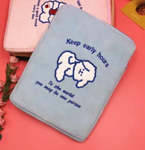 Macro view of soft plush laptop sleeve featuring cute white dog embroidery and blue text.