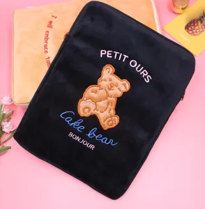 Close-up of cute plush laptop sleeve with bear embroidery, featuring soft velvet texture