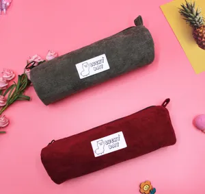 Detailed view of two corduroy pencil cases with alpaca patches in green and red colors.