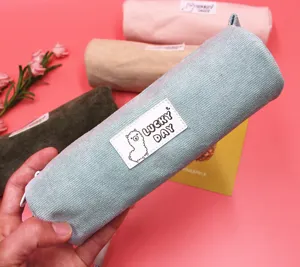 Detailed macro shot of a blue corduroy pencil case featuring a cute alpaca patch design