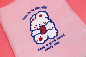 Close-up of cute rabbit embroidery on a soft pink plush laptop sleeve with text