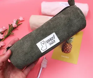 Detailed view of a dark green corduroy pencil case featuring a cute alpaca patch design