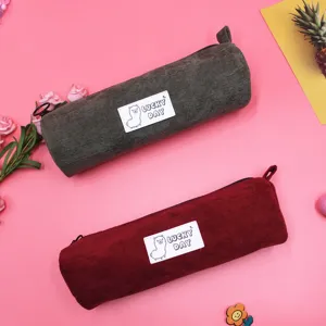Two colorful corduroy pencil cases with cute alpaca patches on a pink background.