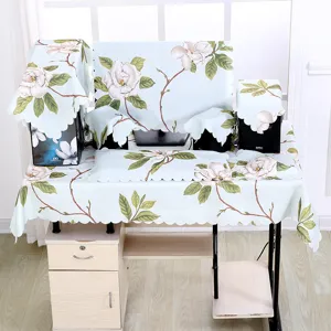 Set aus blauen floralen Computer-Staubschutzhüllen auf Schreibtisch mit Tischtuch