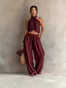 Two-piece burgundy halter crop top and wide-leg trousers set for casual fashion style.