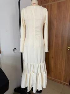 Close-up back view of a retro long-sleeved tiered dress in cream yellow on a mannequin.