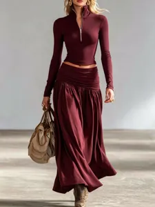 Full shot of elegant burgundy long-sleeve zip-up top and low-waist maxi skirt set