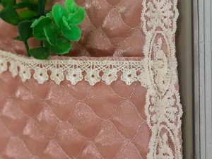 Nahaufnahme der rosa gesteppten Hänge-Aufbewahrungasche mit beiger Spitzenborte und Blumen.
