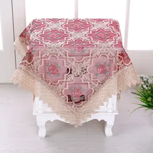 Dettaglio del ricamo a rose rosa e del delicato bordo in pizzo sulla tovaglia multiuso.