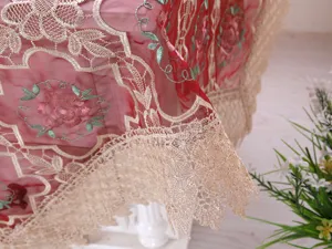 Primo piano di un'elegante tovaglia in filato di vetro rosso con ricami floreali e pizzo.