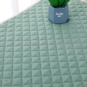 Close-up of green quilted microwave dust cover with diamond pattern and white edge.