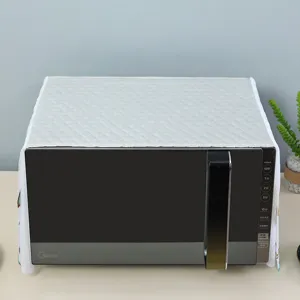 White quilted microwave dust cover with elegant lace trim on a kitchen appliance