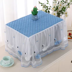 Detailed view of the quilted blue fabric microwave dust cover featuring white lace swan embroidery