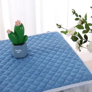 Close-up of a blue quilted fabric dust cover featuring elegant white lace trim for home appliances