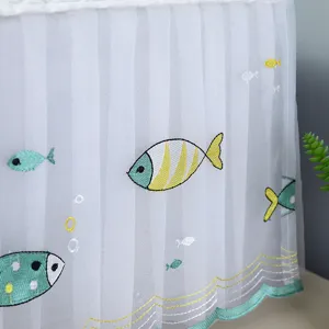 Detailed view of white pleated lace dust cover featuring colorful fish embroidery