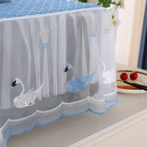Detail view of blue lace dust cover with embroidered swan patterns and mesh frills