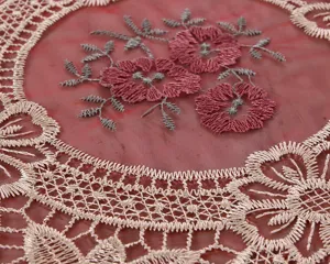 Primo piano di raffinati ricami floreali e bordi in pizzo su tovaglia di organza rosa