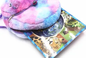 Detailed view of plush tie-dye unicorn backpack showing interior storage capacity with a book