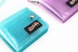 Close-up detail of glittery transparent PVC mini wallets in shimmering cyan and purple hues