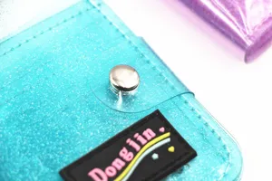 Close-up of a sparkling blue PVC glitter wallet with a secure metal snap button closure.
