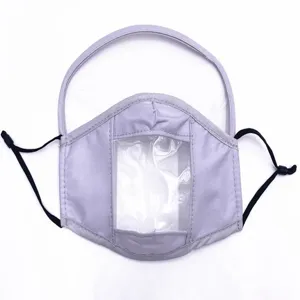 Detailansicht einer lila Stoffmaske mit transparentem Lippenlesefenster und Schild