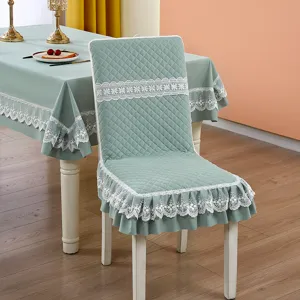 Elegant sage green quilted dining chair cover with white lace ruffles and floral details.