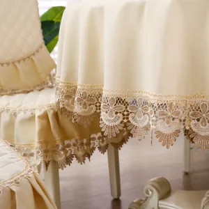 Primo piano dell'elegante pizzo e del tessuto testurizzato della tovaglia rotonda champagne.