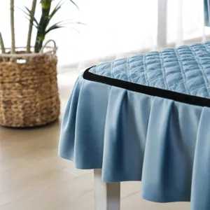 Close-up of a blue quilted velvet chair cover with ruffled skirt and black trim