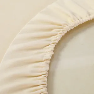 Primo piano del bordo elasticizzato di una tovaglia beige con trama del tessuto.