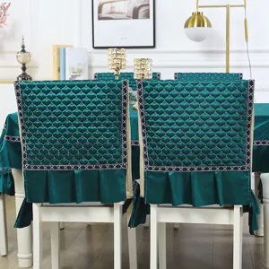 Detail of emerald green quilted chair covers and matching tablecloth in a dining room