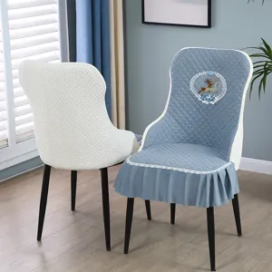 Detailed view of blue quilted dining chair cover with deer embroidery and ruffle skirt