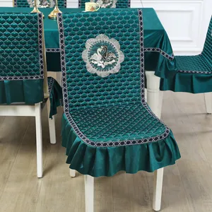Detailed macro view of teal green quilted chair cover with embroidered swan motif design
