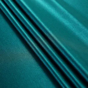 Detail macro shot of elegant teal satin fabric texture showing silky sheen and folds