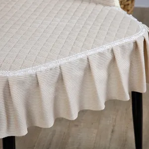 Close-up of quilted beige dining chair cover with elegant lace trim and pleated skirt